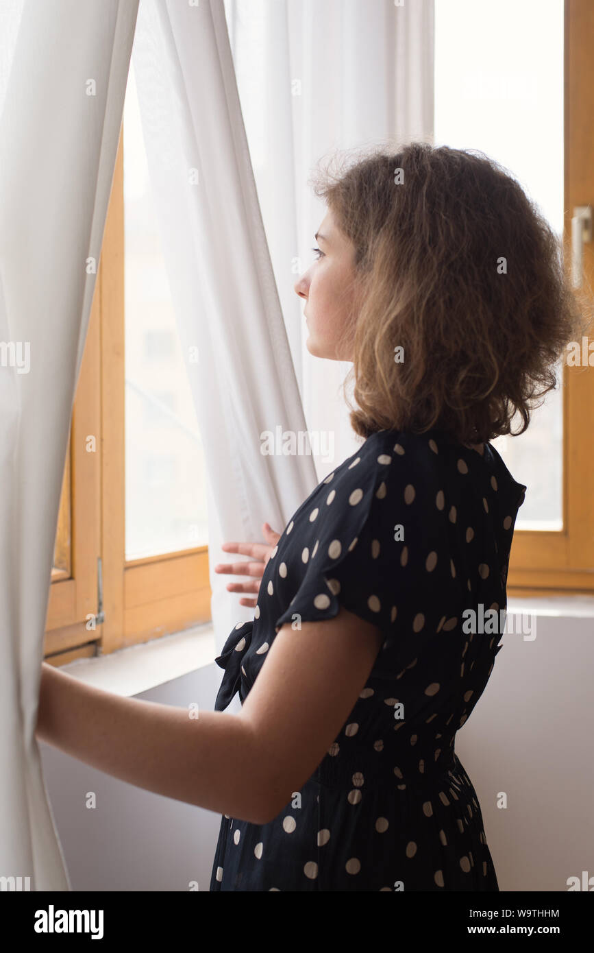 Ragazza adolescente di guardare attraverso una finestra Foto Stock