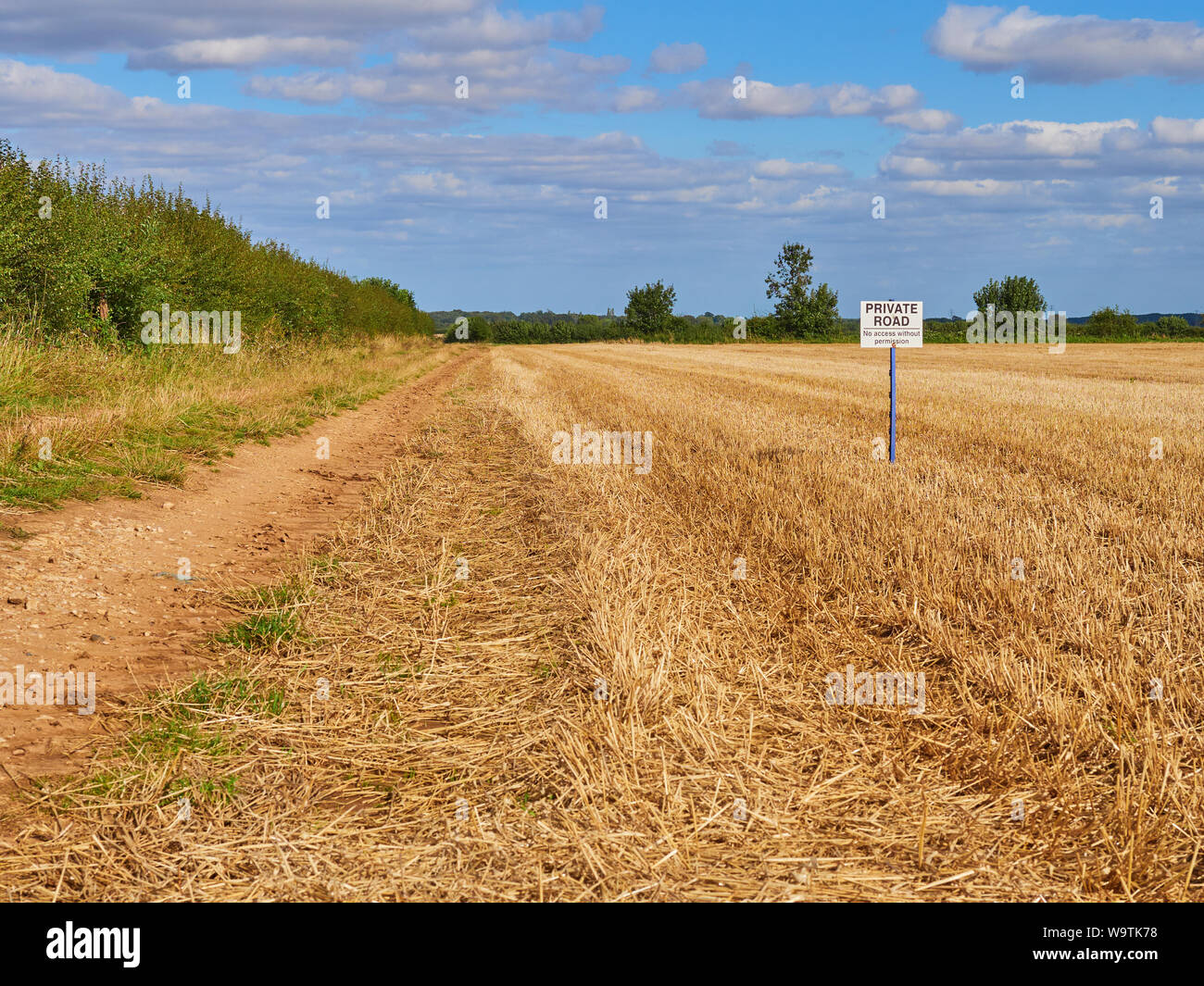 Una strada privata. Nessun accesso senza permesso segno su un post sul lato di una fattoria via accanto a un seminativi campo altezza stoppia Foto Stock