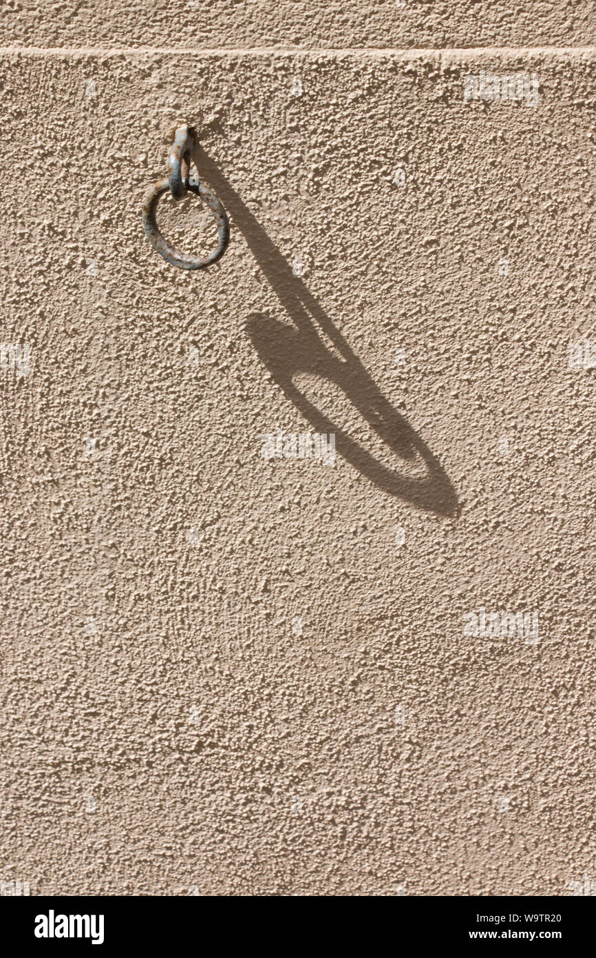 Piccolo anello metallico su giallo parete dipinta con ombra lunga sulla parete Foto Stock