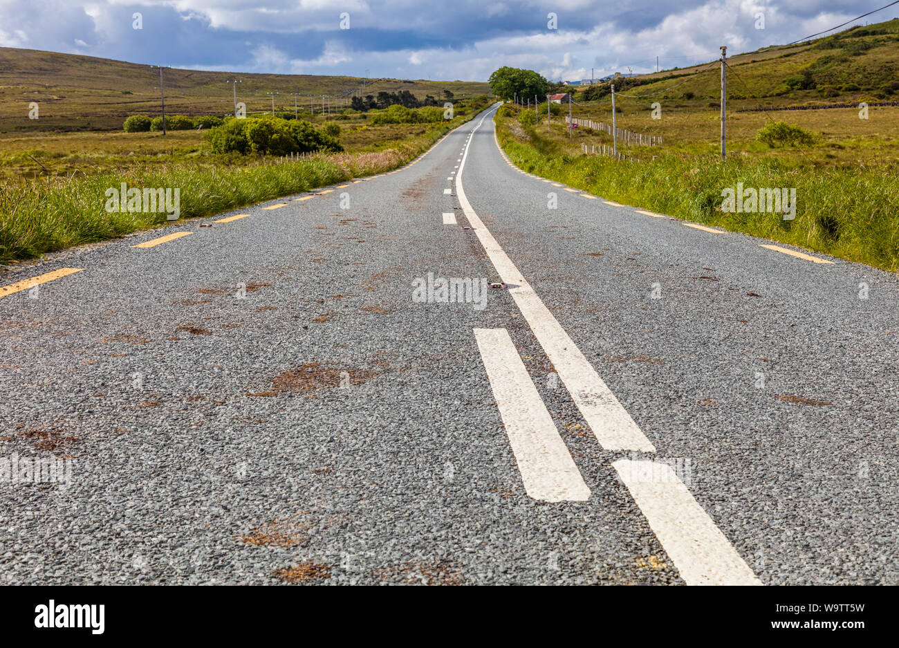 Guardando verso il basso lungo strada asfaltata nelle zone rurali del nord-ovest Irlanda Foto Stock