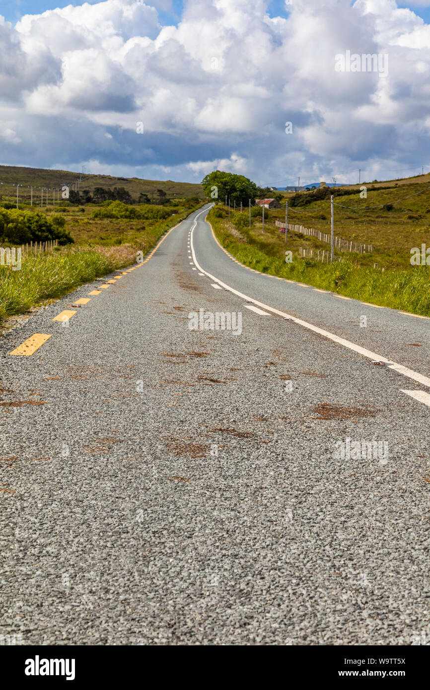 Guardando verso il basso lungo strada asfaltata nelle zone rurali del nord-ovest Irlanda Foto Stock