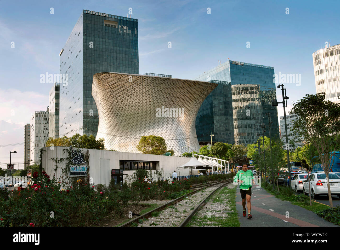 L'uomo jogging, prendendo una pausa dall'ufficio nel quartiere di Polanco. Museo Soumaya e la banca di edifici in background. Città del Messico. Giu 2019 Foto Stock