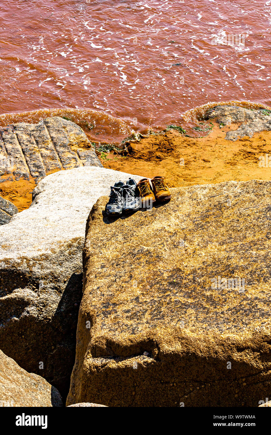 Scarpe abbandonate mentre pagaiando su una spiaggia nel Devon. Foto Stock