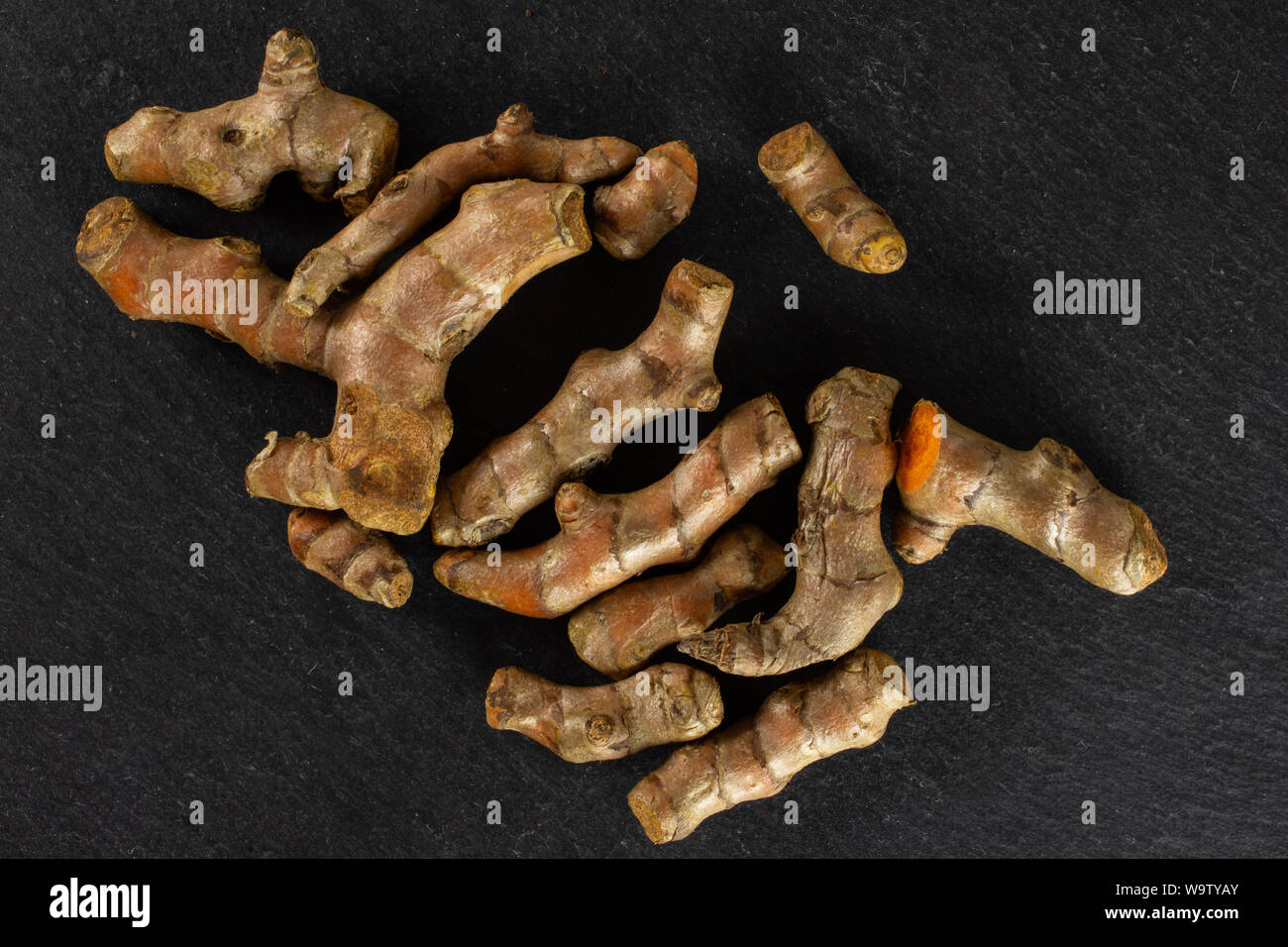 Sacco di intere fresche luminose curcuma rizoma flatlay sulla pietra grigia Foto Stock