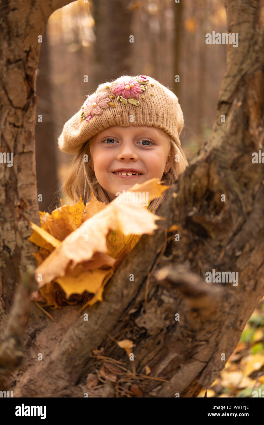Ragazza nella foresta in un tappo marrone in autunno con un buon umore e occhi luminosi Foto Stock