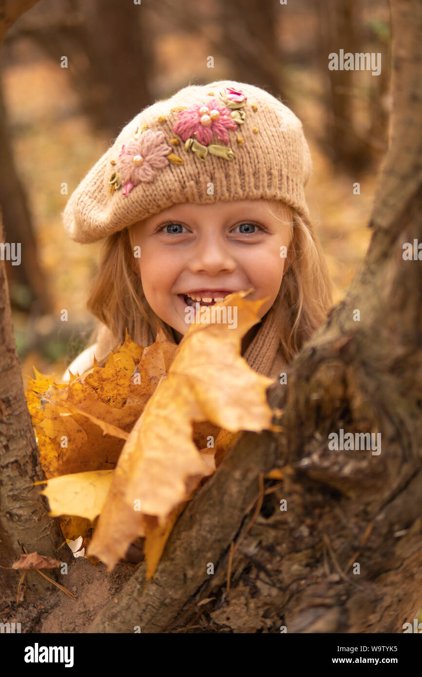 Ragazza nella foresta in un marrone cappello in autunno con un buon umore e occhi brillanti e una foglia Foto Stock