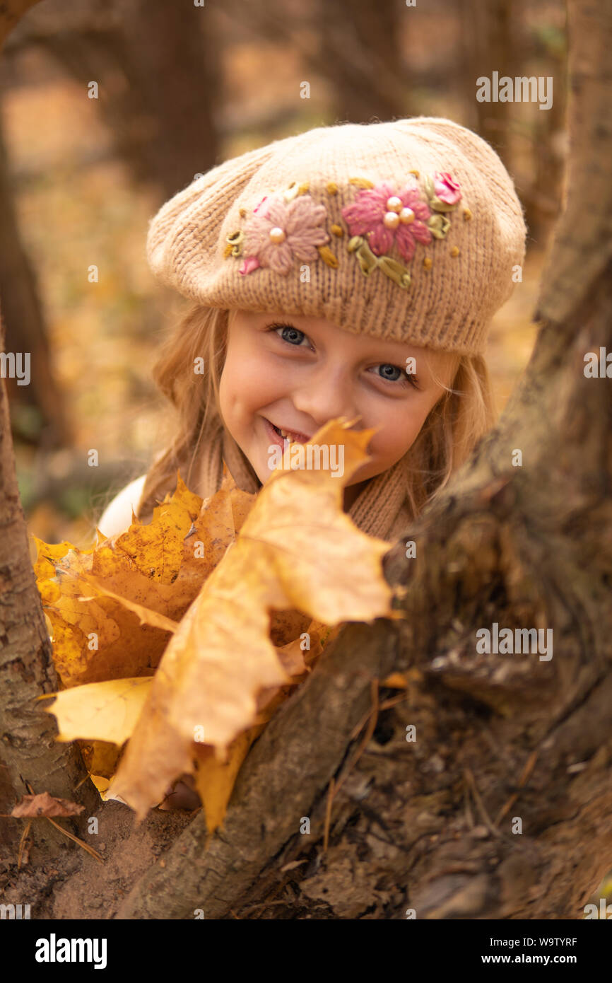 La ragazza in un legno di color marrone in autunno con buon umore sia occhi brillanti e una foglia Foto Stock