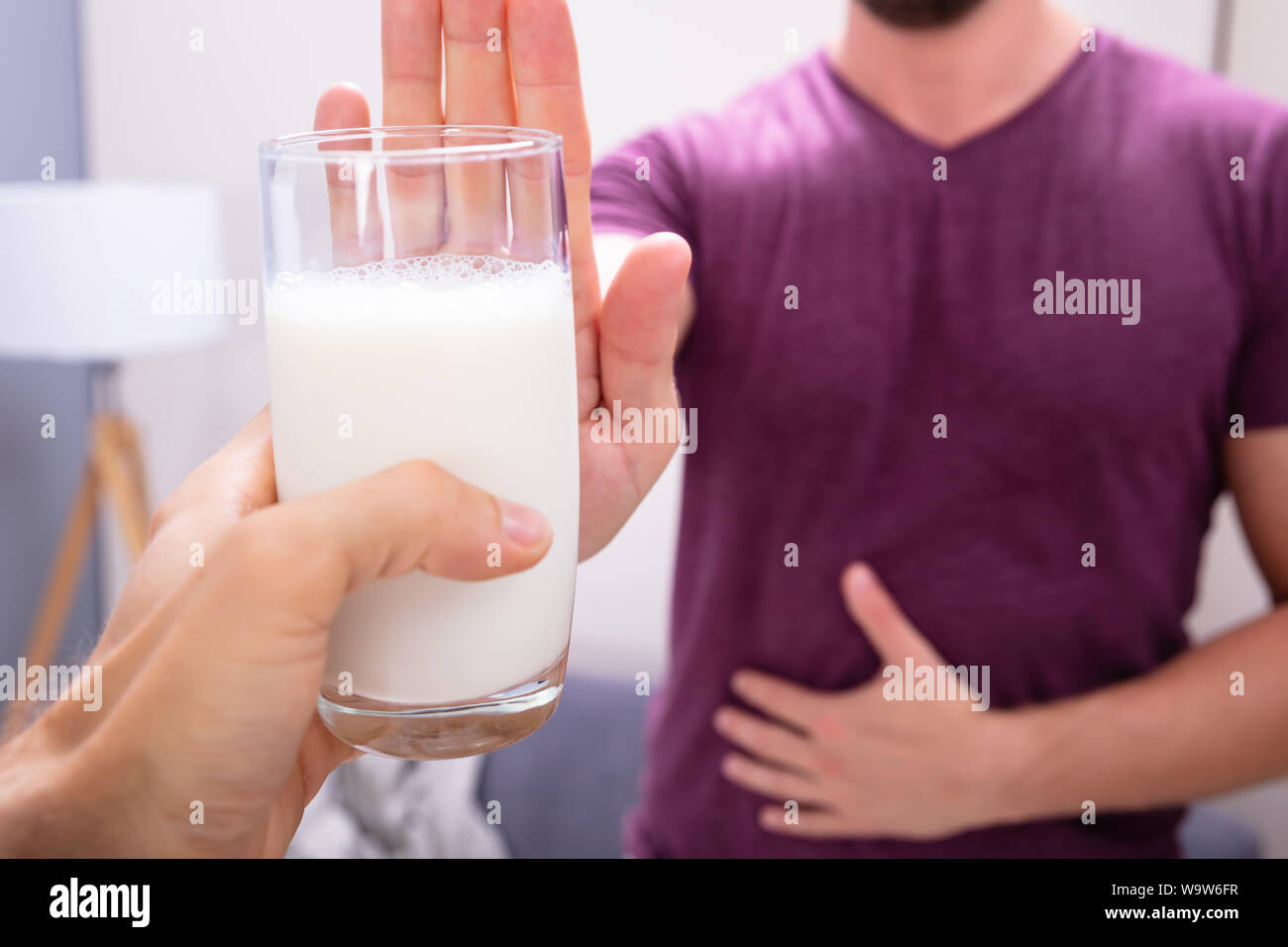 Close-up di un uomo di rigetto di bicchiere di latte offerto da persona a casa Foto Stock