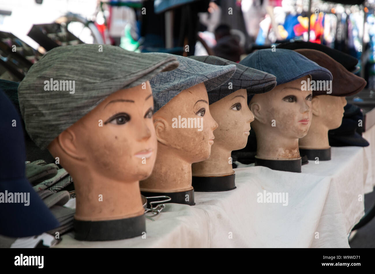 Un display di tappo piatto cappelli sul manichino capi in una fase di stallo nel mercato all'aperto di Dieppe, Francia. Foto Stock