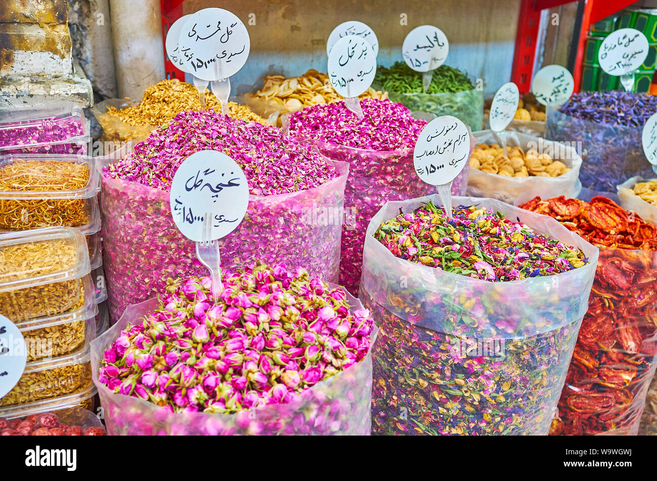 I sacchetti di plastica grandi con secchi rose fiori, petali di fiore mix di tè, noci, frutta e altre erbe e spezie con iraniano schede di prezzo in negozio o Foto Stock