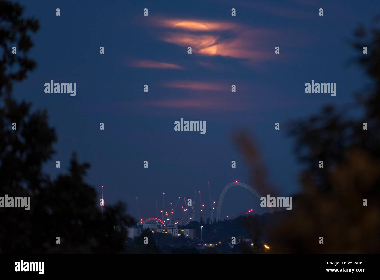 Londra, Regno Unito. Il 15 agosto 2019. La luna piena sorge oltre lo stadio di Wembley iconici arch nel nord ovest di Londra. Il mese di agosto la luna piena è spesso chiamato lo storione Luna, secondo il vecchio contadino di almanacco, perché lo storione (un tipo di pesce) sono più facilmente catturata nel mese di agosto e i primi di settembre. Credito: Stephen Chung / Alamy Live News Foto Stock