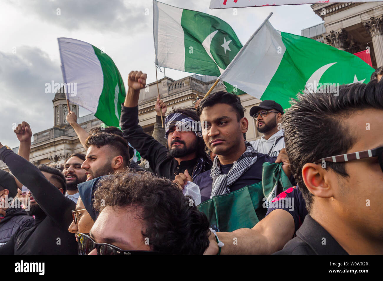 Londra, Regno Unito. Il 15 agosto 2019. Persone con bandiere pakistano protesta dietro il principale segno di protesta in Trafalgar Square sulla Indian Giorno di Indipendenza di condanna gli arresti e le violazioni dei diritti umani nella regione del Kashmir e Modi la revoca dell'articolo 370 della Costituzione indiana. Vogliono che i diritti del popolo del Kashmir e rispettate le risoluzioni delle Nazioni Unite implementato e appello per la libertà per il Kashmir che è stata occupata per molti anni da oltre 700.000 truppe indiane. Peter Marshall / Alamy Live News Foto Stock