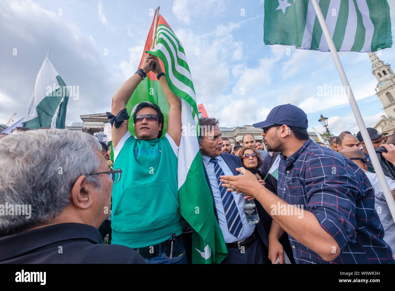 Londra, Regno Unito. Il 15 agosto 2019. Persone con bandiere pakistano protesta dietro il principale segno di protesta in Trafalgar Square sulla Indian Giorno di Indipendenza di condanna gli arresti e le violazioni dei diritti umani nella regione del Kashmir e Modi la revoca dell'articolo 370 della Costituzione indiana. Vogliono che i diritti del popolo del Kashmir e rispettate le risoluzioni delle Nazioni Unite implementato e appello per la libertà per il Kashmir che è stata occupata per molti anni da oltre 700.000 truppe indiane. Peter Marshall / Alamy Live News Foto Stock