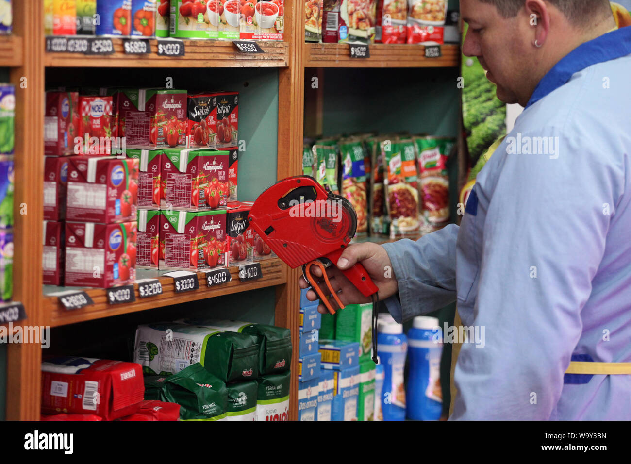 Buenos Aires, Argentina. 14 Ago, 2019. Un dipendente di farina di contrassegni di pacchi con nuovi prezzi dopo questa settimana di turbolenze economiche. I mercati azionari in Buenos Aires sono crollati in seguito alla sconfitta elettorale per il Presidente Macri liberale di governo nelle elezioni primarie. Il principale indice S&P Merval ha perso il 35,5 percento. Il peso argentino ha anche fatto irruzione in. Come risultato, i prezzi sono aumentati in diversi settori. In Argentina si trova in una grave recessione, con il 10,1 per cento di disoccupazione e di oltre il 50 percento di inflazione. Credito: Claudio Santisteban/dpa/Alamy Live News Foto Stock