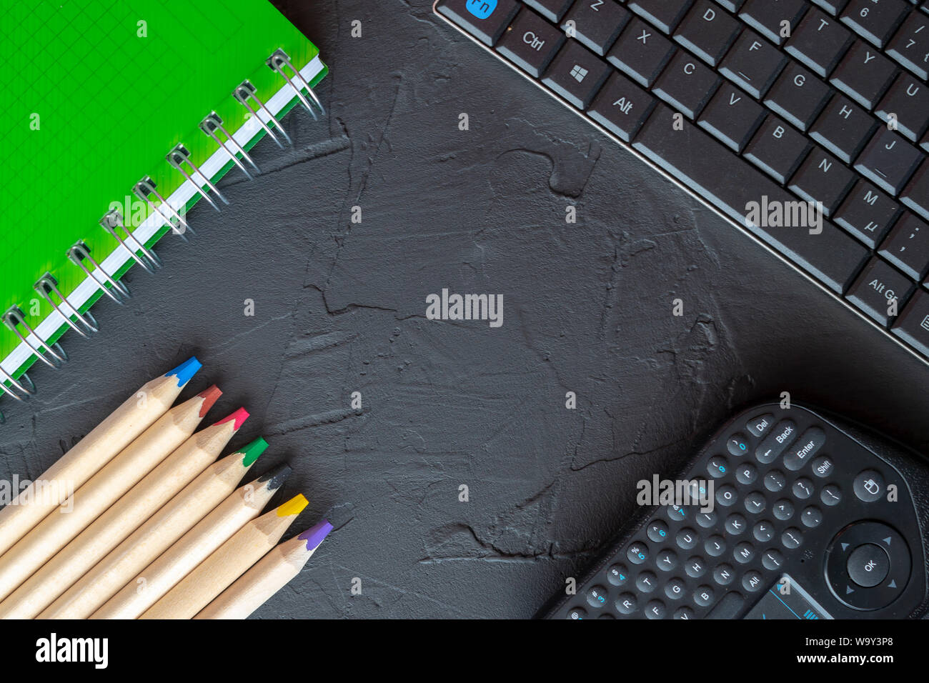 Torna a scuola con sfondo verde anello a spirale legato notebook, matite e tastiere su sfondo nero. Appartamento laico, vista da sopra Foto Stock