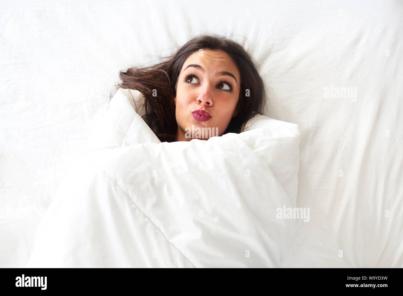 Ritratto di sorridere beautifal donna con la coltre bianca, wake up concept Foto Stock