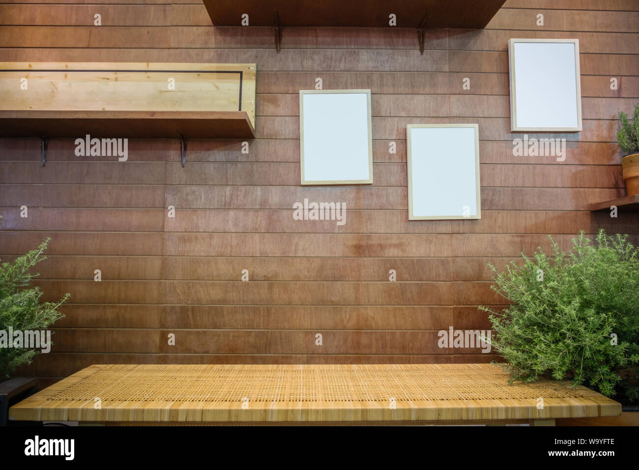 Banco di rattan contro la parete in legno bianco con cornici e ripiano. Rustica sala naturale decorazione di interni. Foto Stock