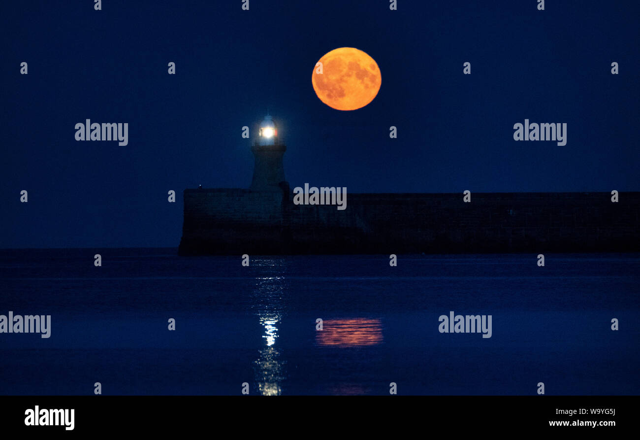 Una luna piena, noto come una luna di storione, sorge su South Shields faro nel nord-est dell'Inghilterra. Foto Stock