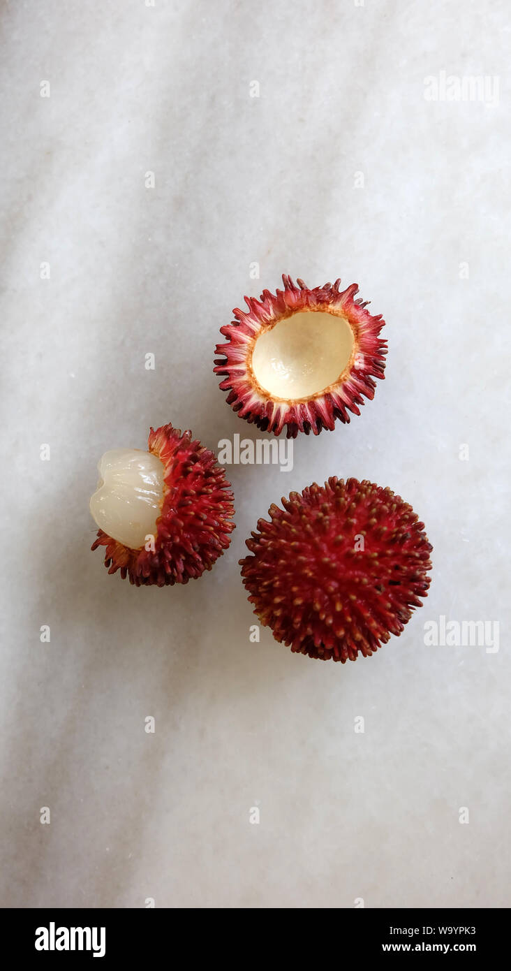 Frutti Pulasan - uno intero e un altro pelato. Nome scientifico Nephelium ramboutan-akea, pulasan è un rosso di frutta tropicale strettamente alleati di rambutan. Foto Stock