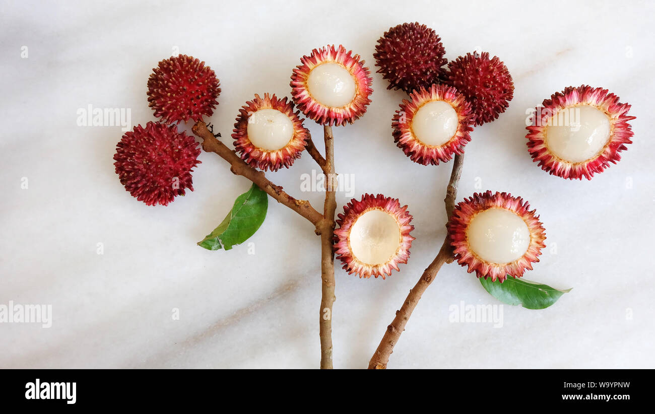 Piatto di laici pulasan frutta, foglie e rami disposti in un mazzo di fiori. Pulasan è un rosso di frutta tropicale dal sud-est asiatico. Foto Stock