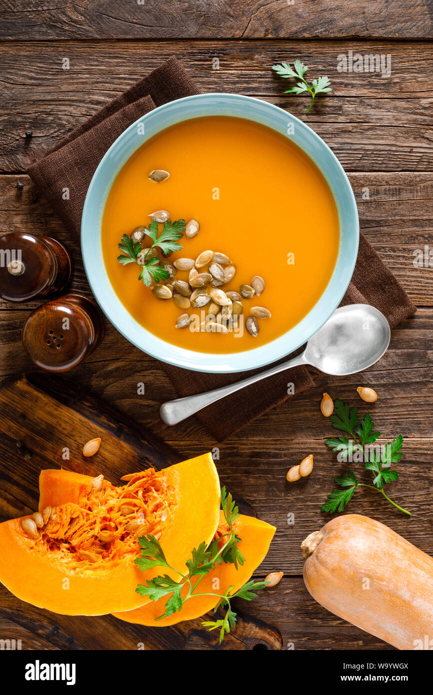 Zuppa di zucca. Zuppa vegetariana con i semi di zucca nella ciotola sul tavolo di legno, vista dall'alto Foto Stock