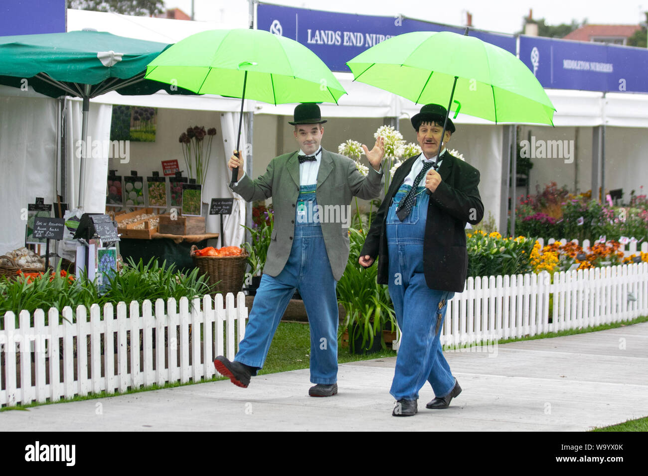 Southport, Merseyside. Regno Unito Meteo. 16 agosto 2019. Washout anticipato come pioggia pesante deluga il Southport Flower Show. Laurel e Hardy lookalikes sopportano la pioggia persistente pesante durante tutta la mattina. Piuttosto ventoso durante il giorno come le attendances sono influenzate dal tempo avverso. Foto Stock