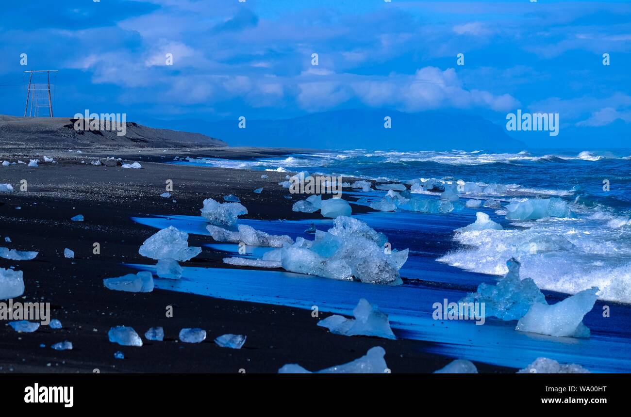 Bellissimo colpo di ghiaccio burgs lavato su riva con montagna e cielo blu sullo sfondo Foto Stock