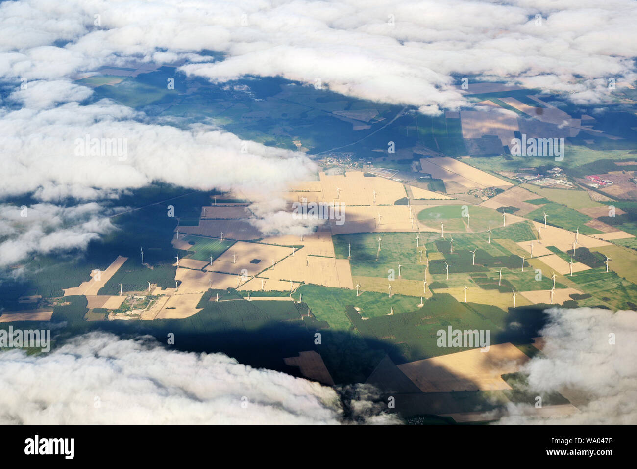 Vista aerea attraverso le nuvole in una fattoria eolica con molte turbine eoliche in un paesaggio agricolo Foto Stock