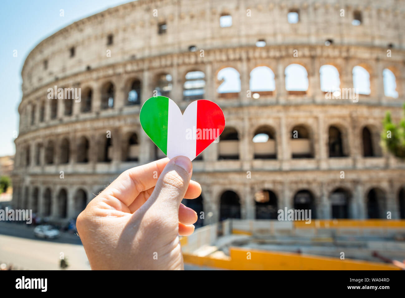 Persona che tiene a forma di cuore Bandiera Italiana davanti al Colosseo, Italia Foto Stock