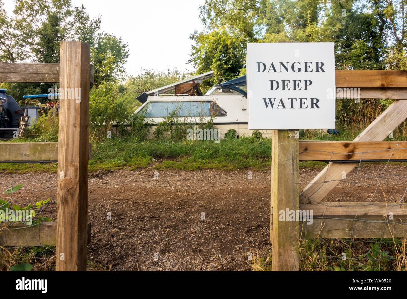 Un segno come si passa attraverso un recinto sul sentiero che costeggia il fiume Kennet a lettura in Berkshire, Regno Unito mette in guardia contro il pericolo di acqua profonda, Foto Stock