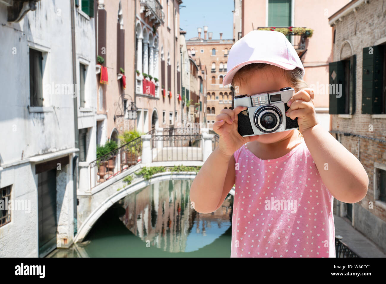 Bambina di scattare una foto sulla fotocamera con case e Canal a sfondo a Venezia Foto Stock