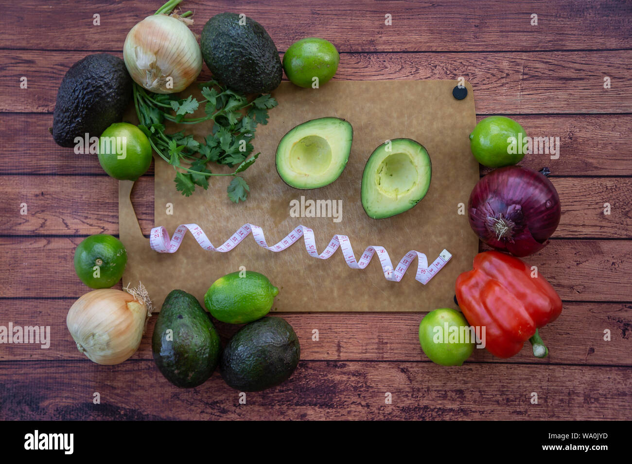 Frazzled faccia con dimezzato avocado, di coriandolo fresco e guacamole ingredienti. Vista superiore del cibo con un frazzled, confuso, sopraffatto faccia. Un sano di Foto Stock