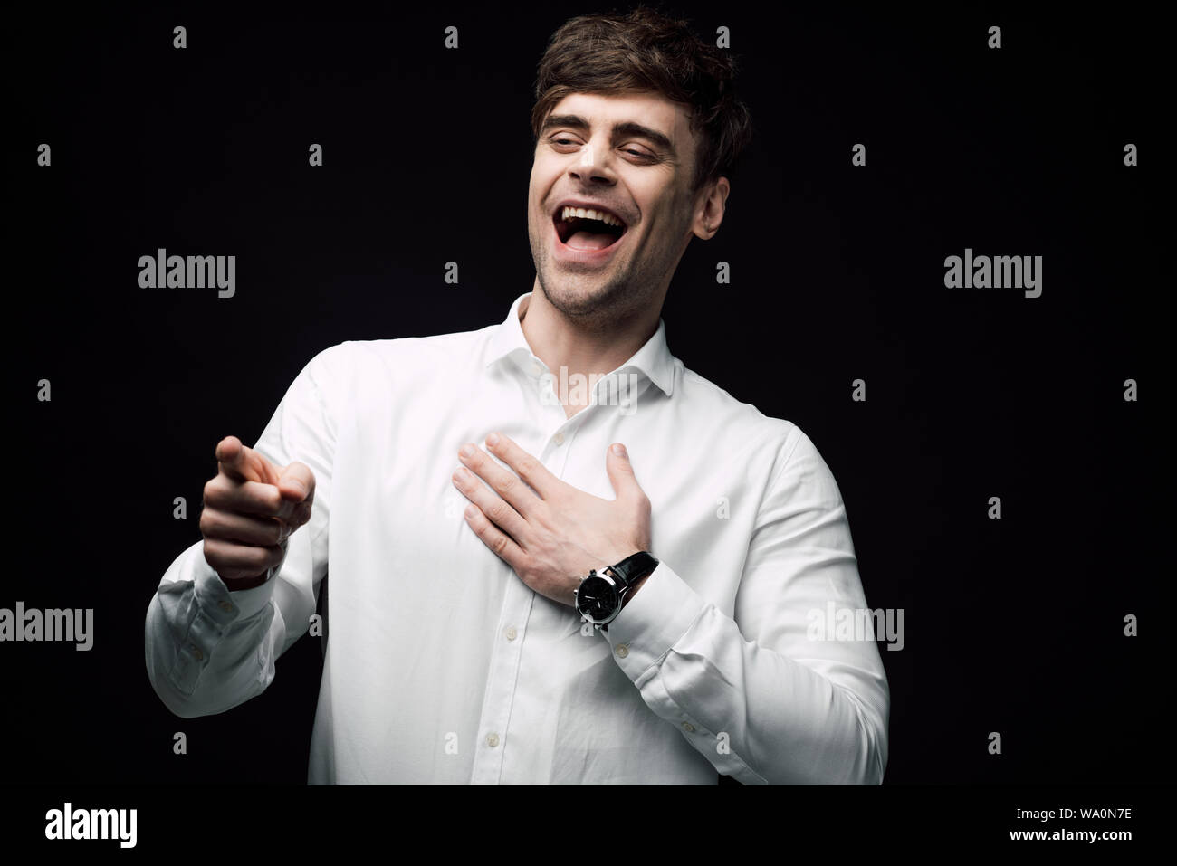 Imprenditore allegro ridendo e indicando con il dito isolato sul nero, emozione umana e il concetto di espressione Foto Stock