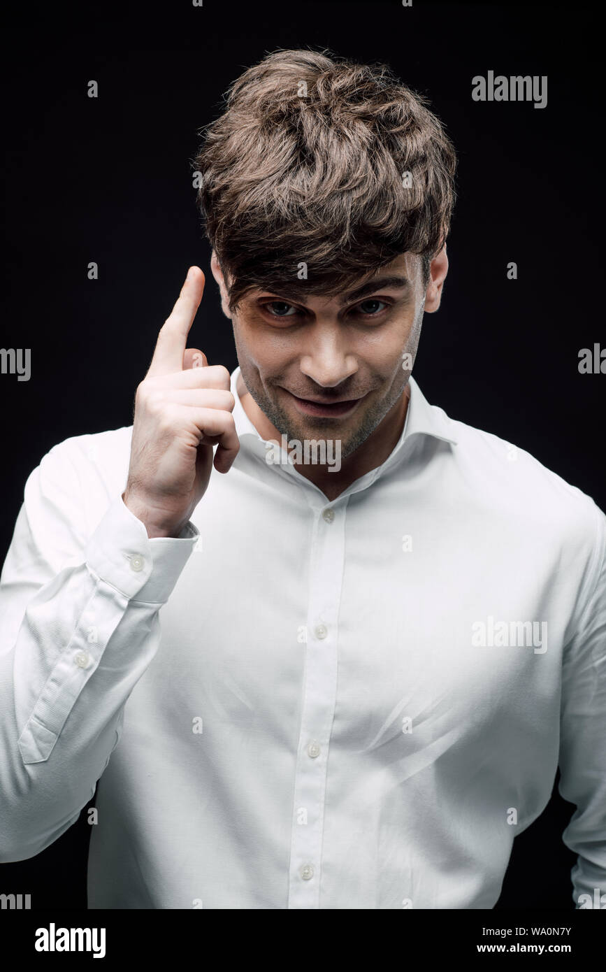 Imprenditore sorridente mostra idea segno isolato sul nero, emozione umana e il concetto di espressione Foto Stock