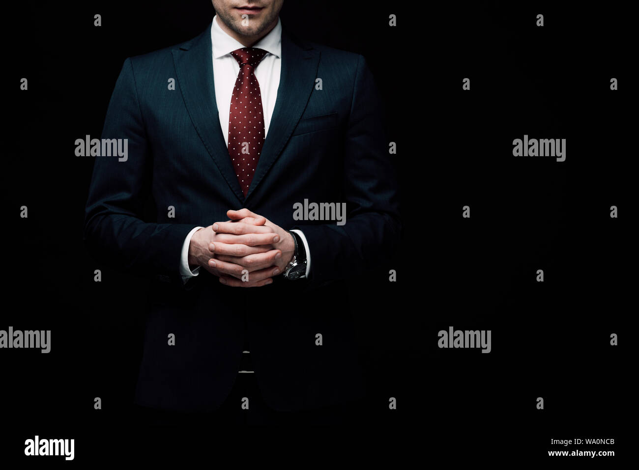 Vista parziale di imprenditore fiducioso in piedi con le mani chiuse isolate su nero, emozione umana e il concetto di espressione Foto Stock