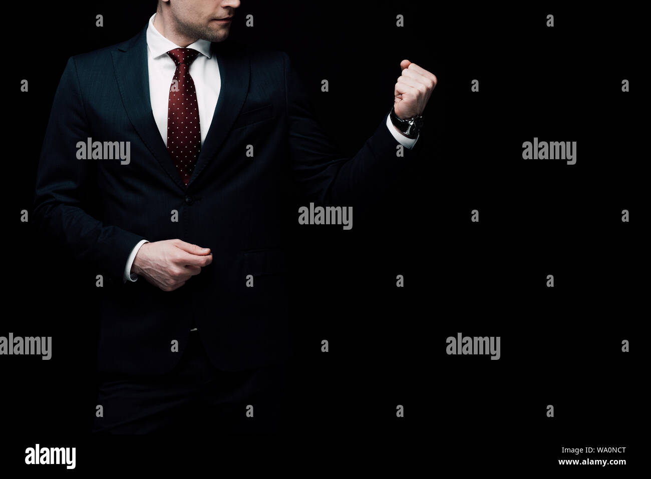 Vista ritagliata della rabbia imprenditore pugno mostrando isolato sul nero, emozione umana e il concetto di espressione Foto Stock