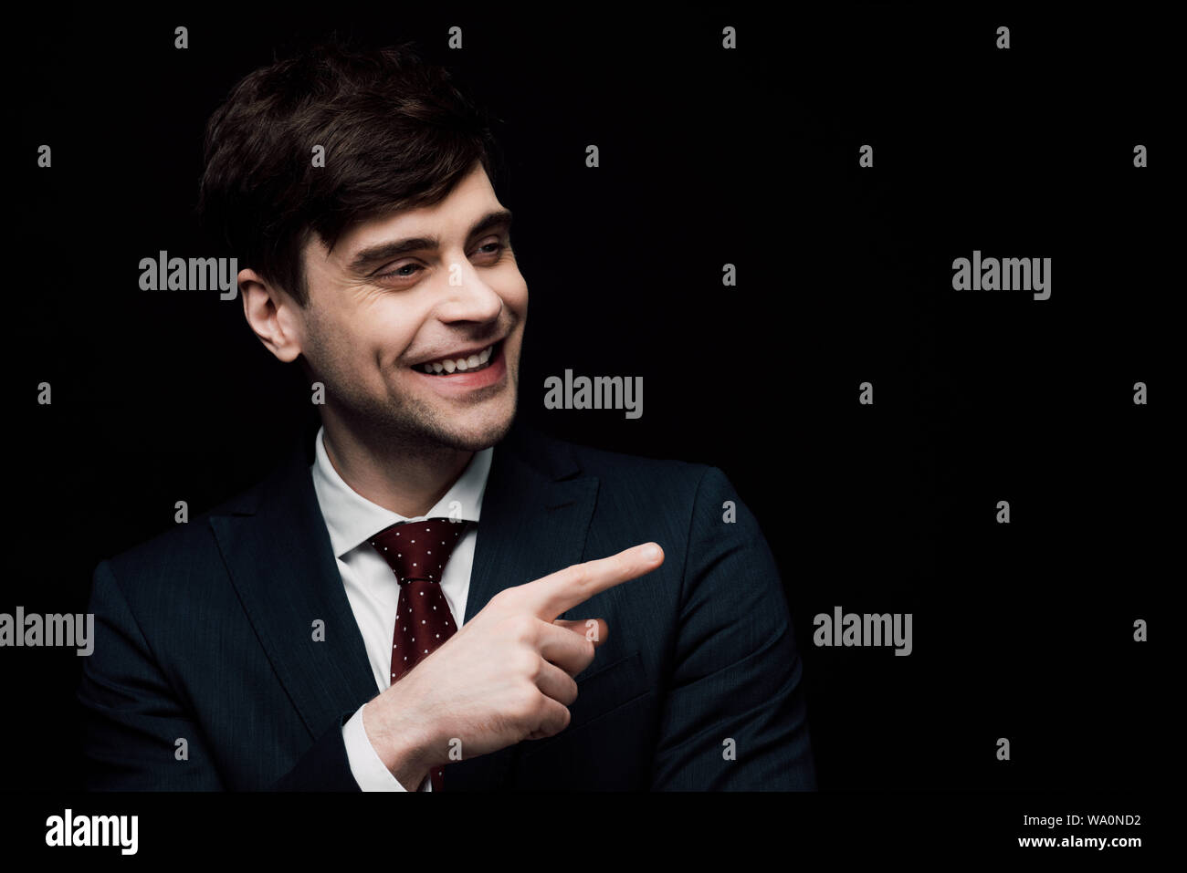 Imprenditore allegro puntando con il dito e guarda lontano isolati su nero, emozione umana e il concetto di espressione Foto Stock