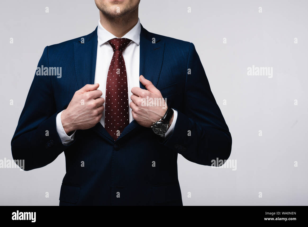 Vista ritagliata della fiducia imprenditore toccando suit isolati su grigio, emozioni umane e concetto di espressione Foto Stock