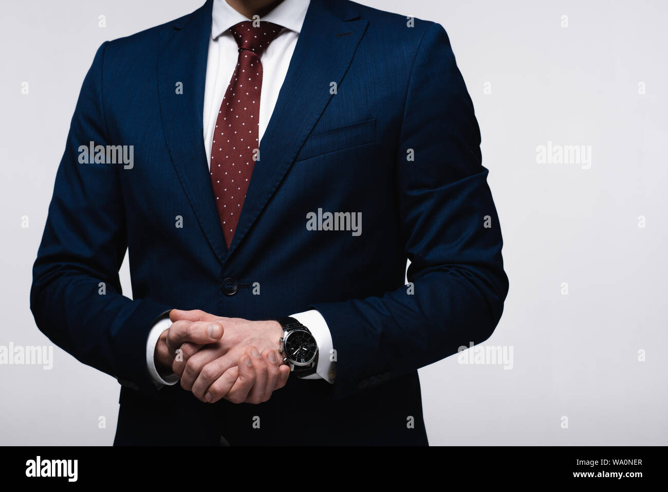 Vista parziale di fiduciosa imprenditore con le mani chiuse isolate su grigio, emozioni umane e concetto di espressione Foto Stock