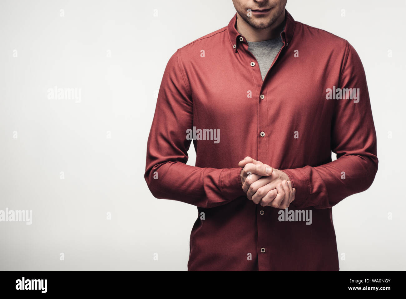 Vista ritagliata dell uomo con le mani chiuse isolate su grigio, emozioni umane e concetto di espressione Foto Stock
