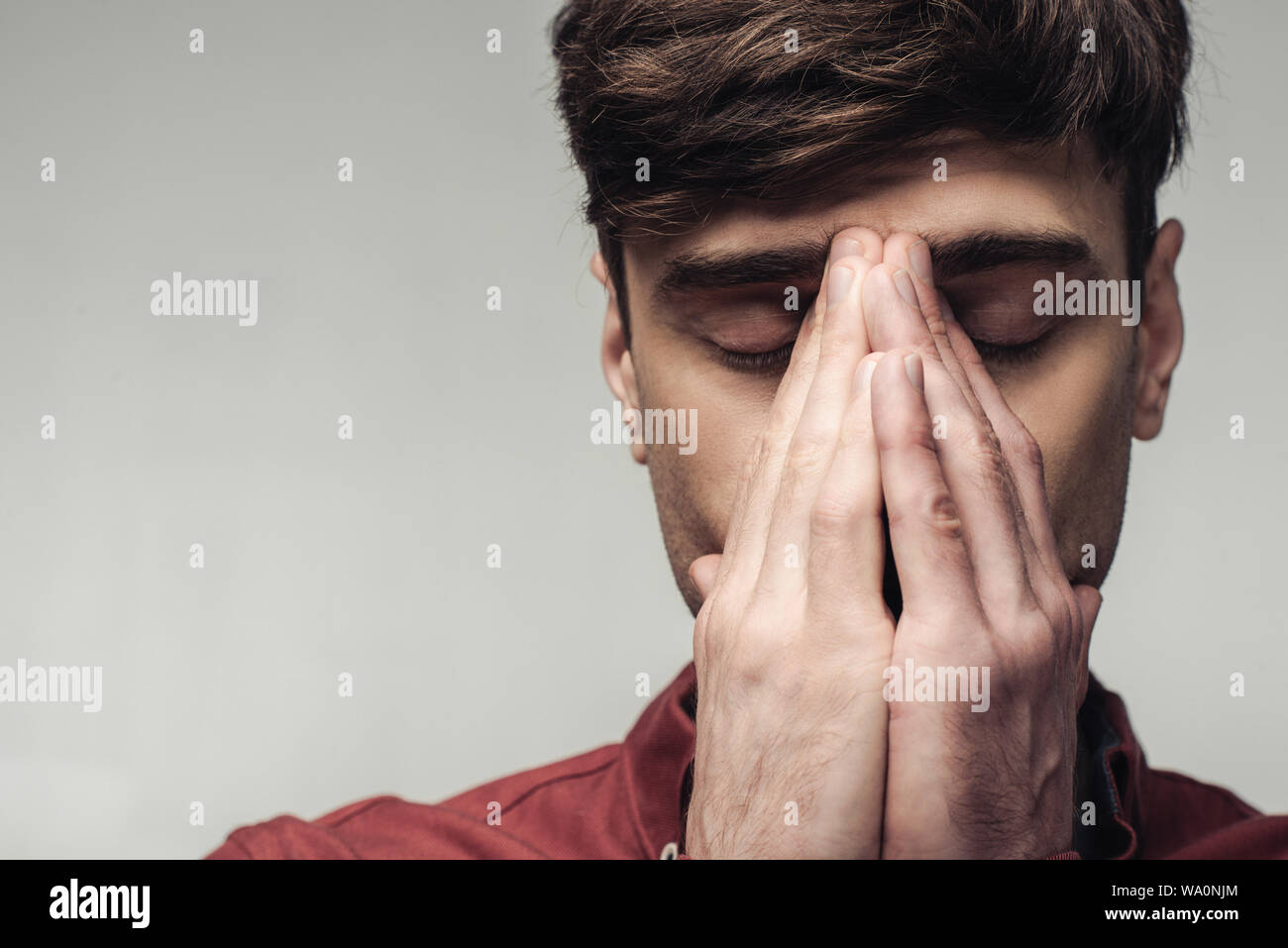 Turbare l uomo con gli occhi chiusi che ricopre la faccia con le mani isolate su grigio, emozioni umane e concetto di espressione Foto Stock