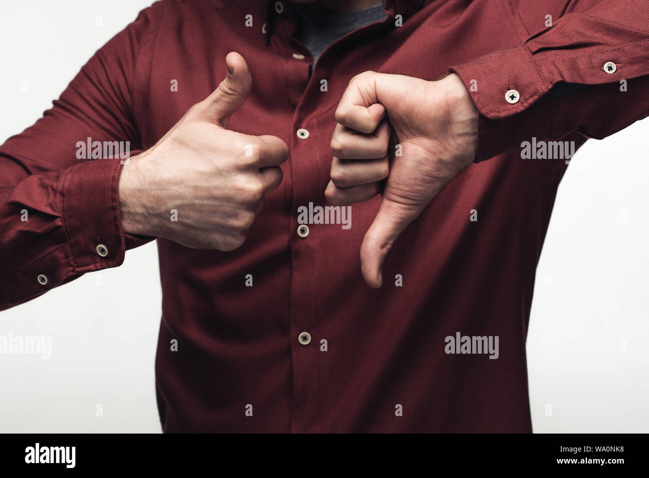 Vista parziale dell'uomo che mostra il pollice in alto e il pollice verso il basso isolati su grigio, emozioni umane e concetto di espressione Foto Stock