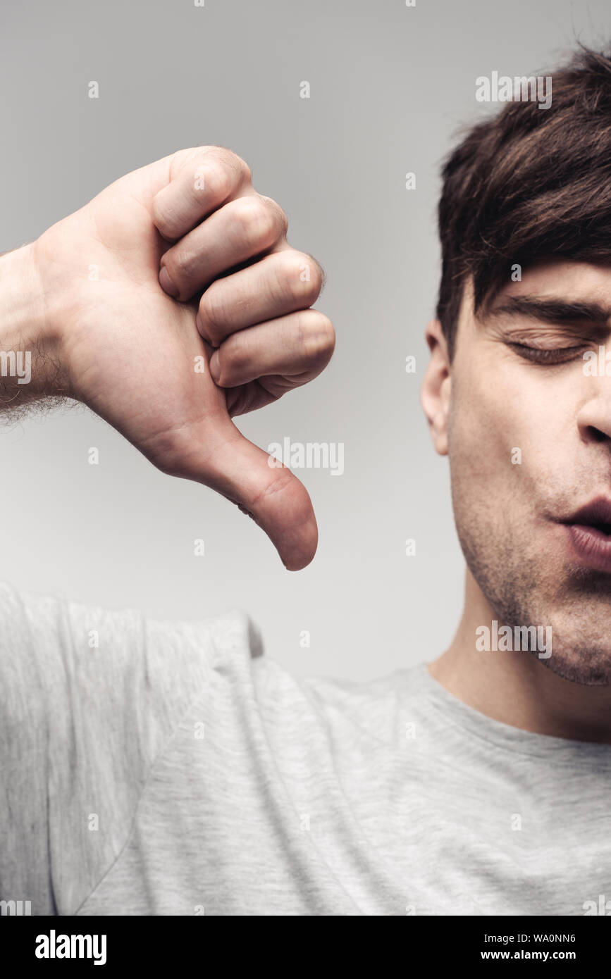 Orinato uomo mostra pollice in alto isolato su grigio, emozione umana e il concetto di espressione Foto Stock