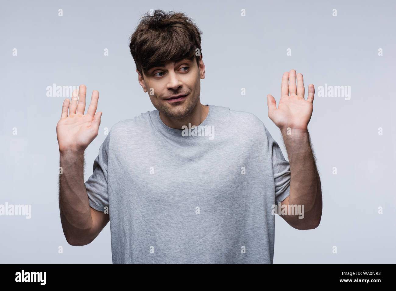 Uomo sorridente mostra rinunciare al gesto e guardando lontano isolati su grigio, emozioni umane e concetto di espressione Foto Stock