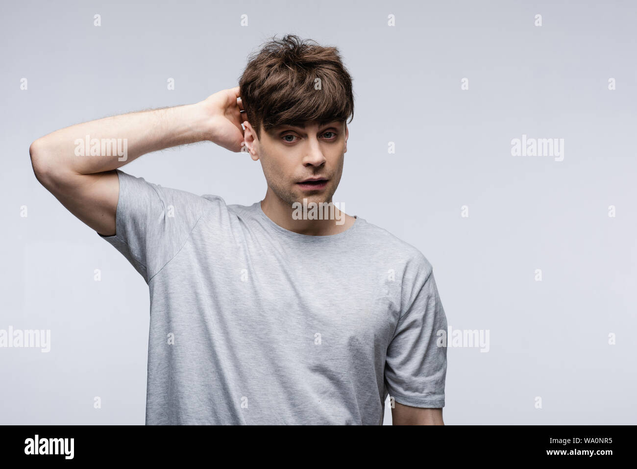 Riflessivo azienda man mano dietro la testa isolata sul grigio, emozioni umane e concetto di espressione Foto Stock