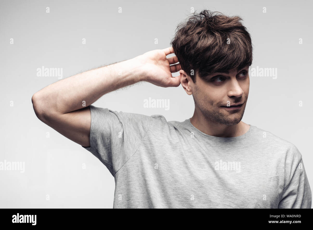 Sorridente sognante azienda man mano dietro la testa isolata sul grigio, emozioni umane e concetto di espressione Foto Stock