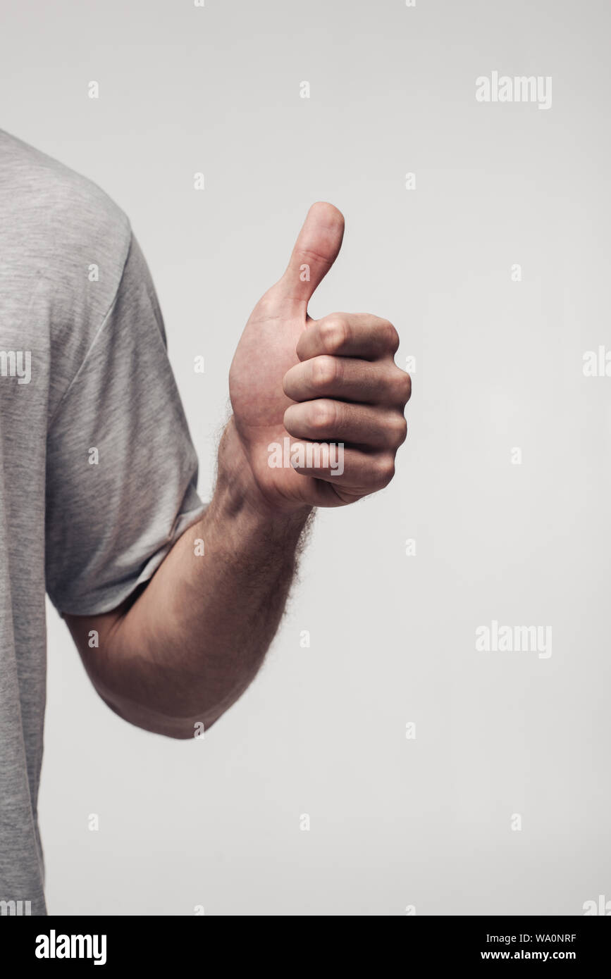 Vista parziale dell'uomo che mostra il pollice in alto isolato su grigio, emozione umana e il concetto di espressione Foto Stock