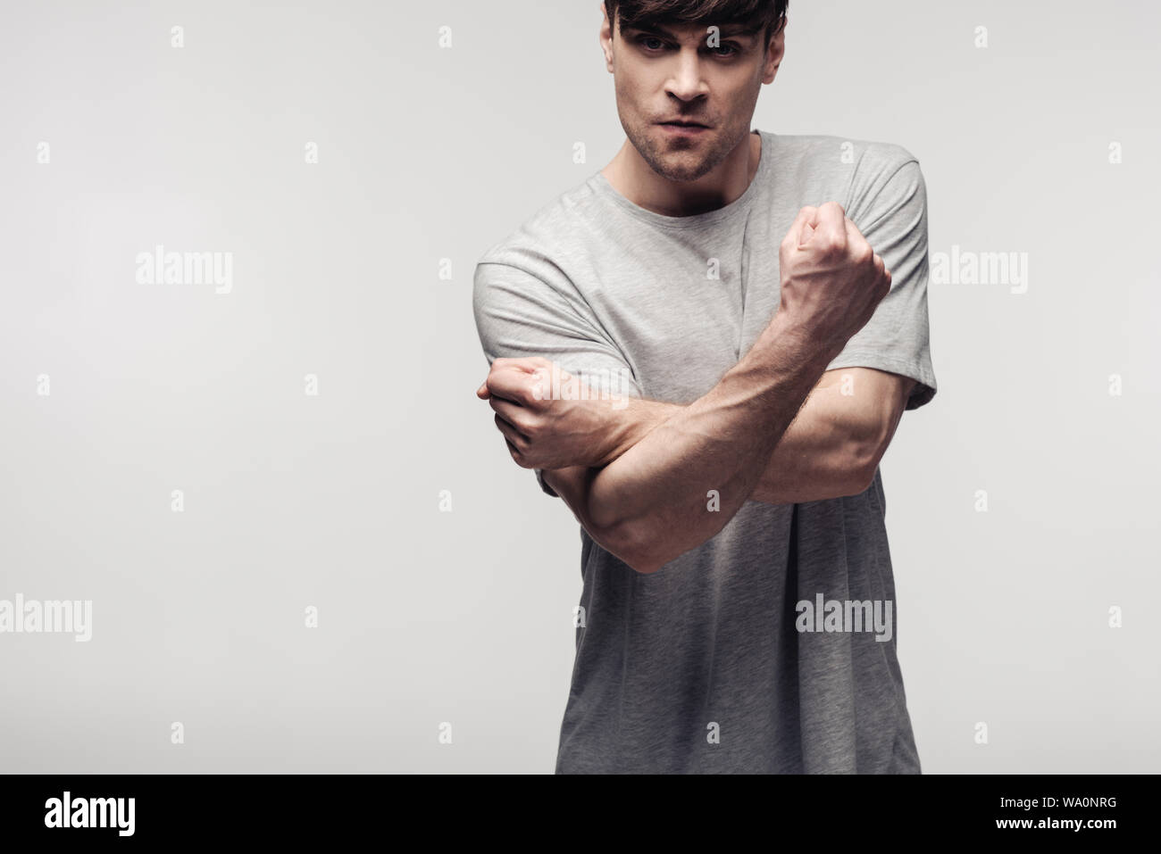 Irritato uomo gesticolando mentre guardando la telecamera isolata sul grigio, emozioni umane e concetto di espressione Foto Stock