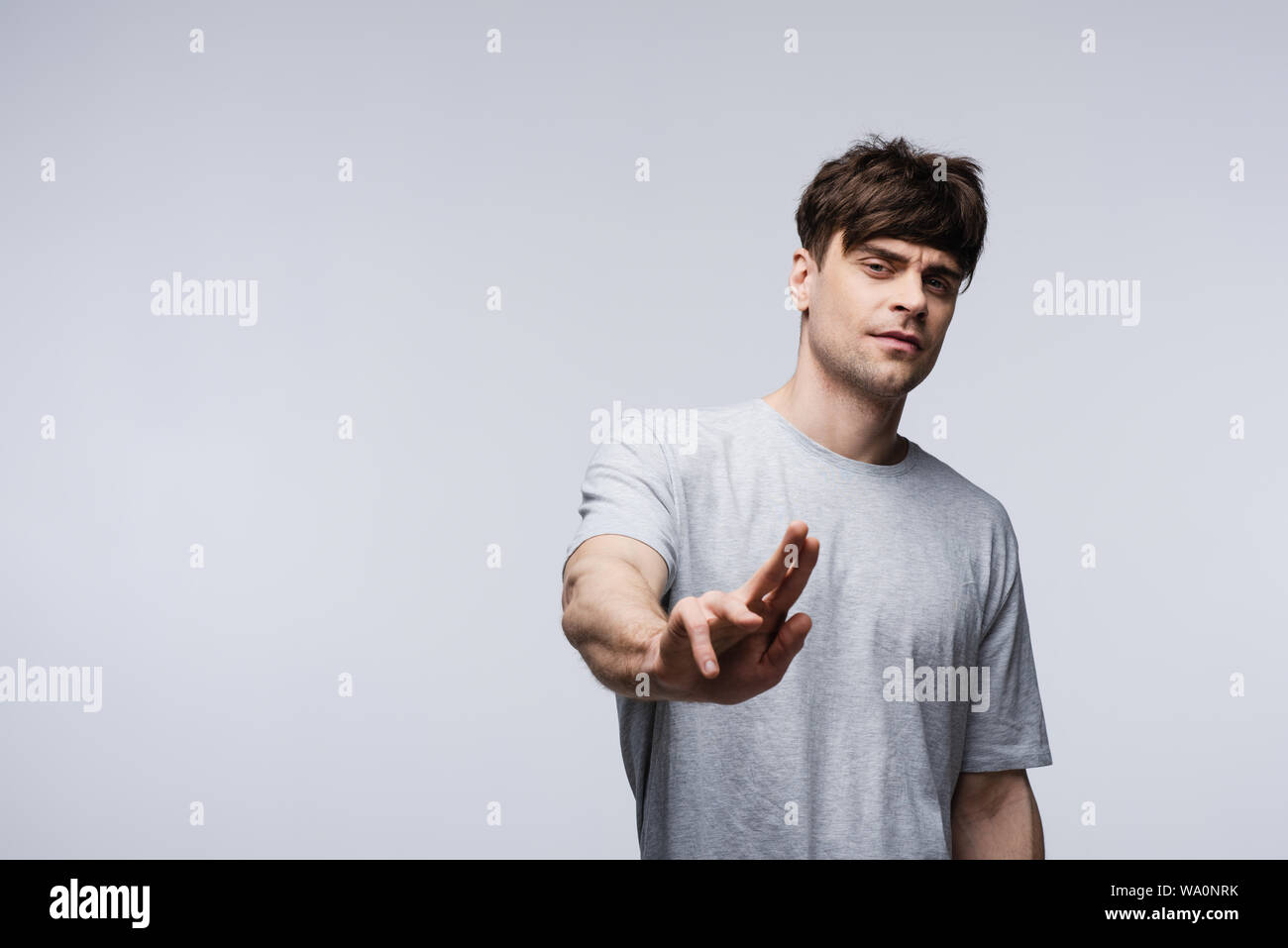 Orinato uomo mostra stop gesto isolato sul grigio, emozioni umane e concetto di espressione Foto Stock