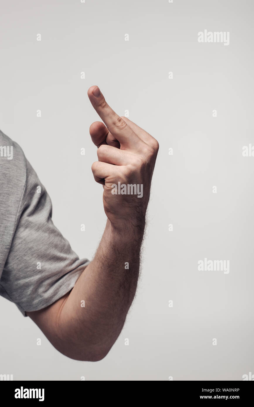 Vista parziale dell'uomo che mostra il dito medio isolato sul grigio, emozioni umane e concetto di espressione Foto Stock